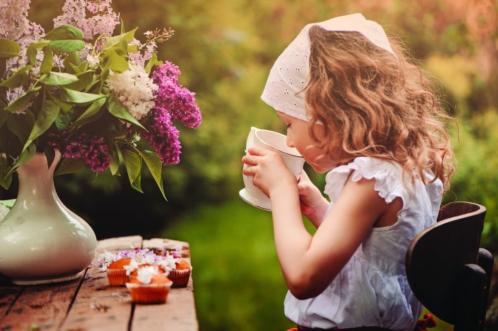 cute child girl on cozy outdoor tea party in spring garden with